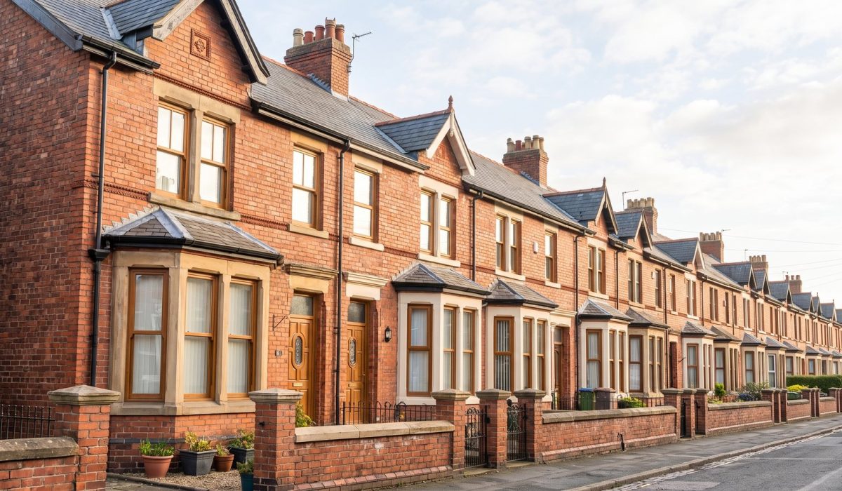 A row of red brick Victorian terraced houses in a northern English city on a bright sunny morning, bay windows, low front walls