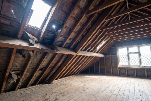 A stripped British loft revealing unexpected problems: a cracked roof tile letting in a pinhole of daylight