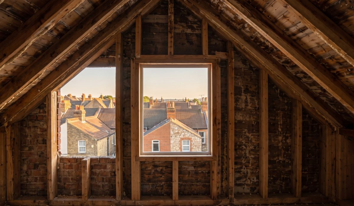A wide sunny view over British rooftops towards a clear open horizon at golden hour brightness, chimney stacks and tiled roofs receding