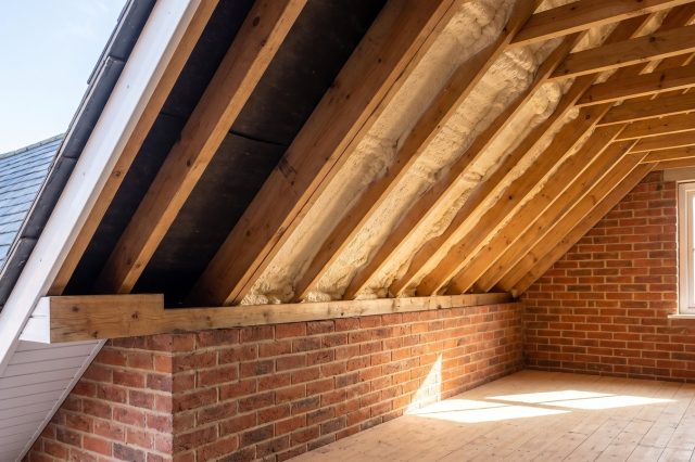 A British roof eaves in bright daylight showing clear airflow: ventilated soffit, open gap at the wall plate